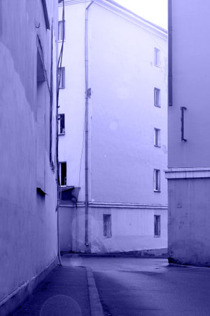Narrow street with small road and sidewalk between building houses in old town district, vertical image in violet purple lilac tones, concept of color 2022 very periの写真素材