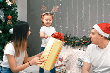 Cozy family christmas, father mother and child girl daughter play and have fun on bed with gifts, happy cheerful xmas holiday together, authentic festive lifestyleの写真素材
