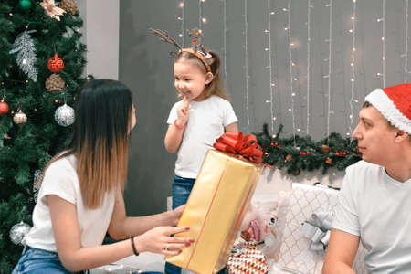 Cozy family christmas, father mother and child girl daughter play and have fun on bed with gifts, happy cheerful xmas holiday together, authentic festive lifestyleの写真素材