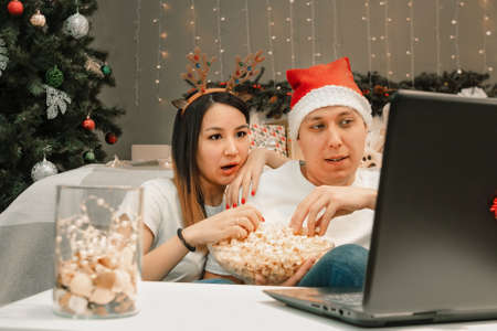 Christmas family couple, young man and woman watch video on laptop at home in bed room, happy fun and cozy xmas holiday together at movie night, authentic festive lifestyleの写真素材