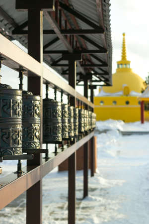 Rows of traditional spinning prayer wheels with tibetan holy sacred mantras at winter temple...