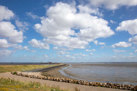 Wadden Sea at Schiermonnikoog, low tide on the coast, the ferry landing point in the distance and a beautiful skyscape all little sheep cloudsの写真素材