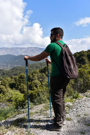 Young man looking the landscape with clouds while he is taking a break from hikingの写真素材