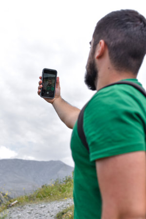 Closeup of a man taking a selfie in the nature with his mobile phone