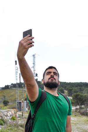 Young man taking a selfie in the nature with his mobile phoneの写真素材