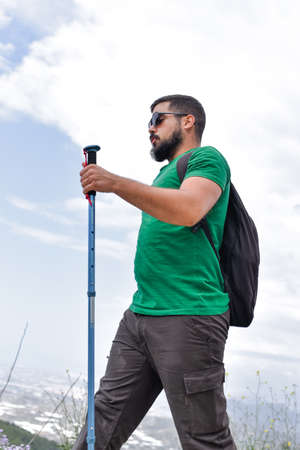 Man on a hiking day holding a hiking pole while he is walkingの写真素材