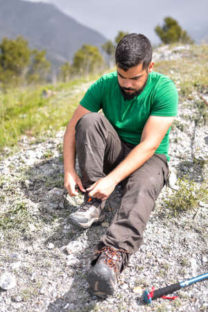 Man tying laces of hiking boots sitting on the groundの写真素材