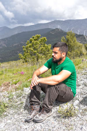 Young man admiring the landscape while he is sitting on the groundの写真素材
