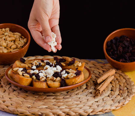 Hand adding cheese to a capirotada, traditional mexican dessert