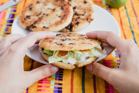 Mexican eating gordita de chicharron stuffed with onion, coriander, lettuce, spicy chile sauce and cheeseの写真素材