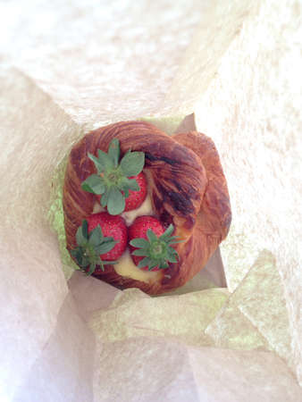 Top view of a paper bag with a strawberry pastry. 