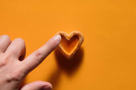 Food romantic concept heart shaped cookie on bright orange backgroundの写真素材