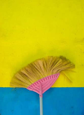 Cleaning old broom leaning against the  old wall yellow and blueの写真素材