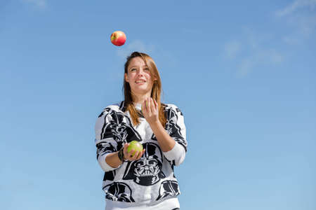 A young woman juggling with three crunchy and healthy applesの写真素材