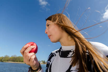 Young woman eats healthy with a red apple on a nice dayの写真素材