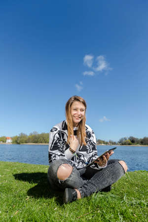 A young laughing and holding a tablet in her handの写真素材