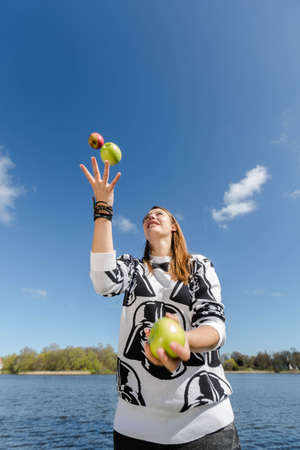 Young healthy woman juggling with three crunchy applesの写真素材