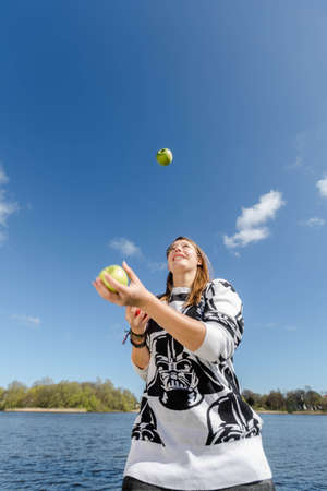 Young healthy woman juggling with three crunchy applesの写真素材