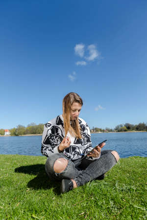 Young woman runs through her hair and looking at her tabletの写真素材