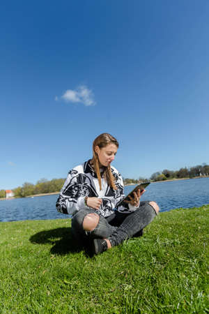Student sitting on the campus and working with her tabletの写真素材