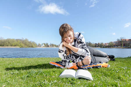 Young woman reading a book and runs his hand through her hairの写真素材