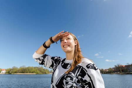 A woman has her hands on his forehead and looks during nice weather in the distanceの写真素材