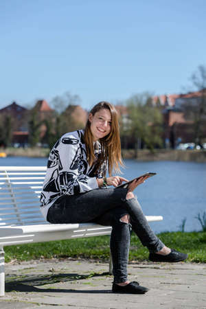 Woman reading something on her tablet and laughs during nice weatherの写真素材
