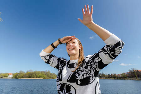 A young woman gazing into the distance, waving a handの写真素材