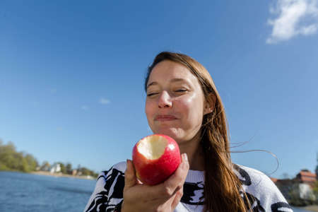 A young woman eating a healthy apple in the open air on a beautiful dayの写真素材
