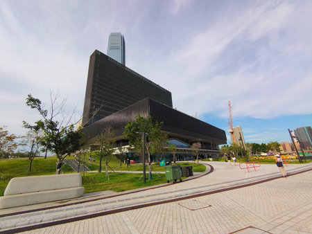 Hong Kong - 08.29.2021: Wide-angle side view of the Mplus Museum with lawn surrounding and visitors...