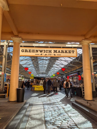 London, UK - 10.24.2021: Visitors busy browsing the market stalls, viewed from inside the portico entrance of Greenwich Market with sunlight coming through the glass roofのeditorial素材