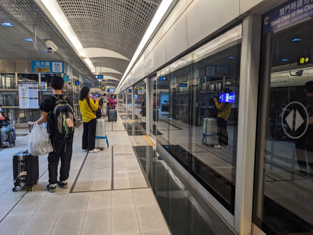 Taipei, Taiwan - 11.21.2022: Passengers with luggage waiting for a Taoyuan International Airport MRT train on the Airport Terminal 1 platform in front of the glass doors during the pandemicのeditorial素材