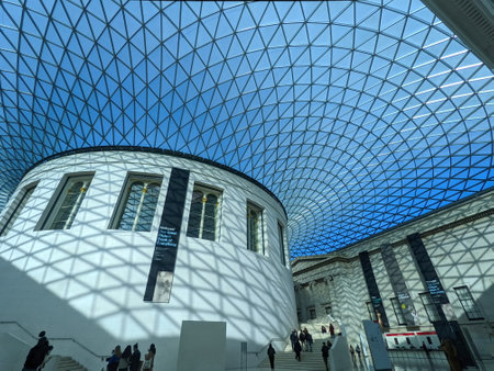 London, UK - 11.02.2021: Visitors walking in the Great Court of the British Museum on a sunny day with sunlight coming through the curved tessellated glass roofのeditorial素材