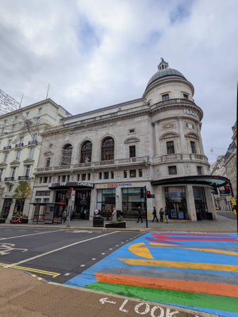 London, UK - 11.14.2021: A colourful traffic light-controlled pedestrian crossing with pedestrians walking outside Vue Cinema London - Piccadilly on Regent Street Saint James under a cloudy blue skyのeditorial素材