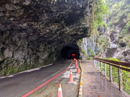 Taroko, Taiwan - 11.26.2022: A car waiting at the entrance to Swallow Grotto Trail with separated road and an empty pavement leading into darkness alongside cliff before 403 earthquake during pandemicのeditorial素材