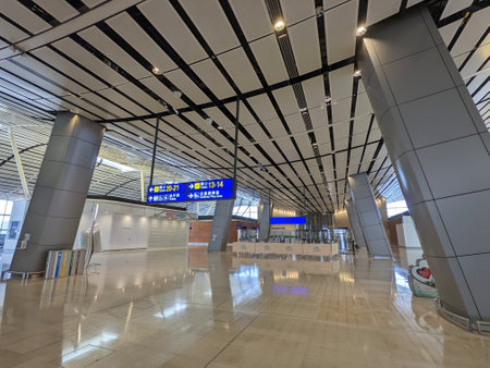 Hong Kong International Airport - 11.21.2022: The empty North Satellite Concourse with closed shops, escalators, and rubbish bins under signage to gates from the ceiling during the pandemicのeditorial素材