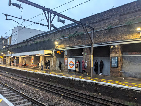 Passengers waiting on the platform of Stoke Newington Overground station on an overcast evening
