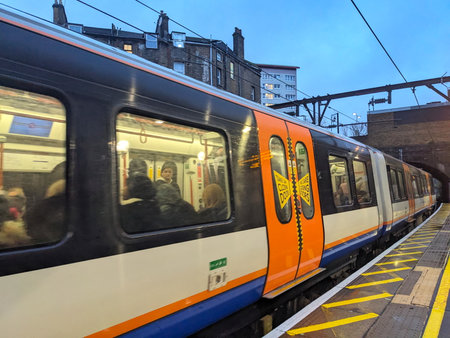 London Overground Train Arrives at Stoke Newington Station Platform with Commuters and City Skyline