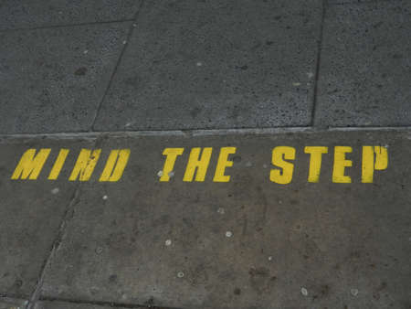 Mind the Step warning advice in yellow over gray train station floor