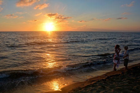 Girl and boy at the sundown on the beachの写真素材