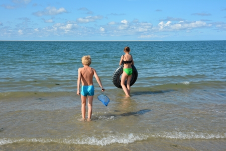 Two children standing on the beach before the seaの写真素材
