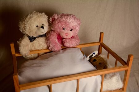 Teddy bear parents are worried at the bed of their sick child, teddy bear child with clinical thermometerの写真素材