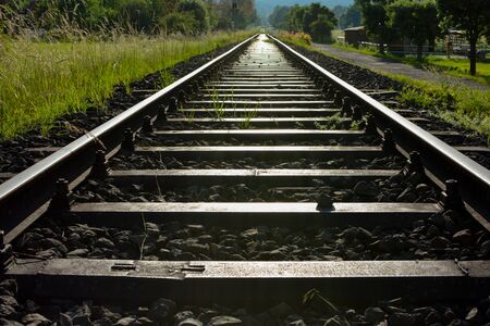Endless Railway tracks between green fields in the evening lightの写真素材