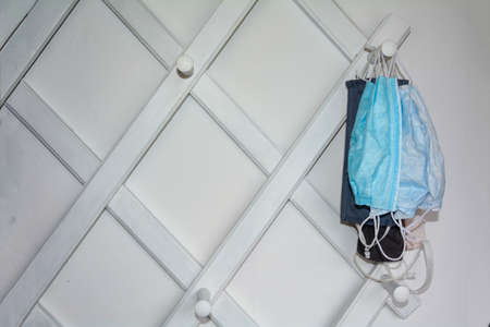 White hallway cloakroom with a hung respirator and a hat on the left