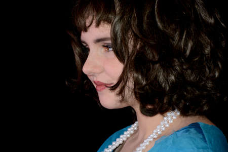 Portrait of a young woman in blue dress and brown hair, from front and laughing, with black...
