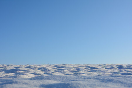 A field with lots of white snow and blue skies on the horizonの写真素材