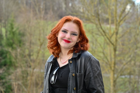 Young woman wearing black clothes and smiling face, standing in green nature