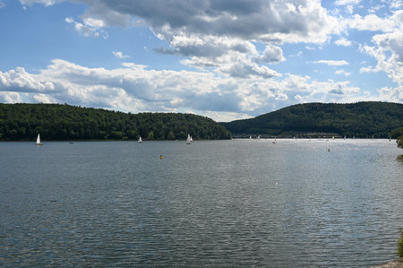 View of the lake Edersee with sailing boats, blue sky and clouds, in Hesse, Germanyの写真素材