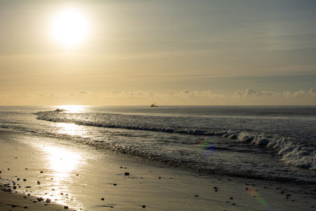 Sunrise on the sea around a sandy beach with a boat