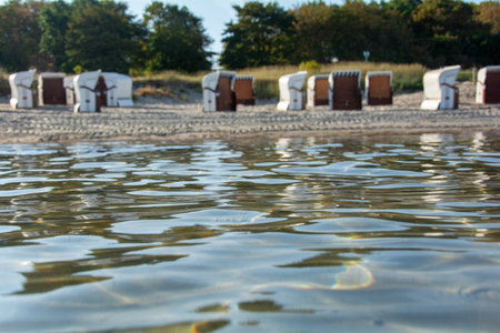 View of blurred beach chairs on the sandy beach from the water of the Baltic Sea, on Poel, Germanyの写真素材